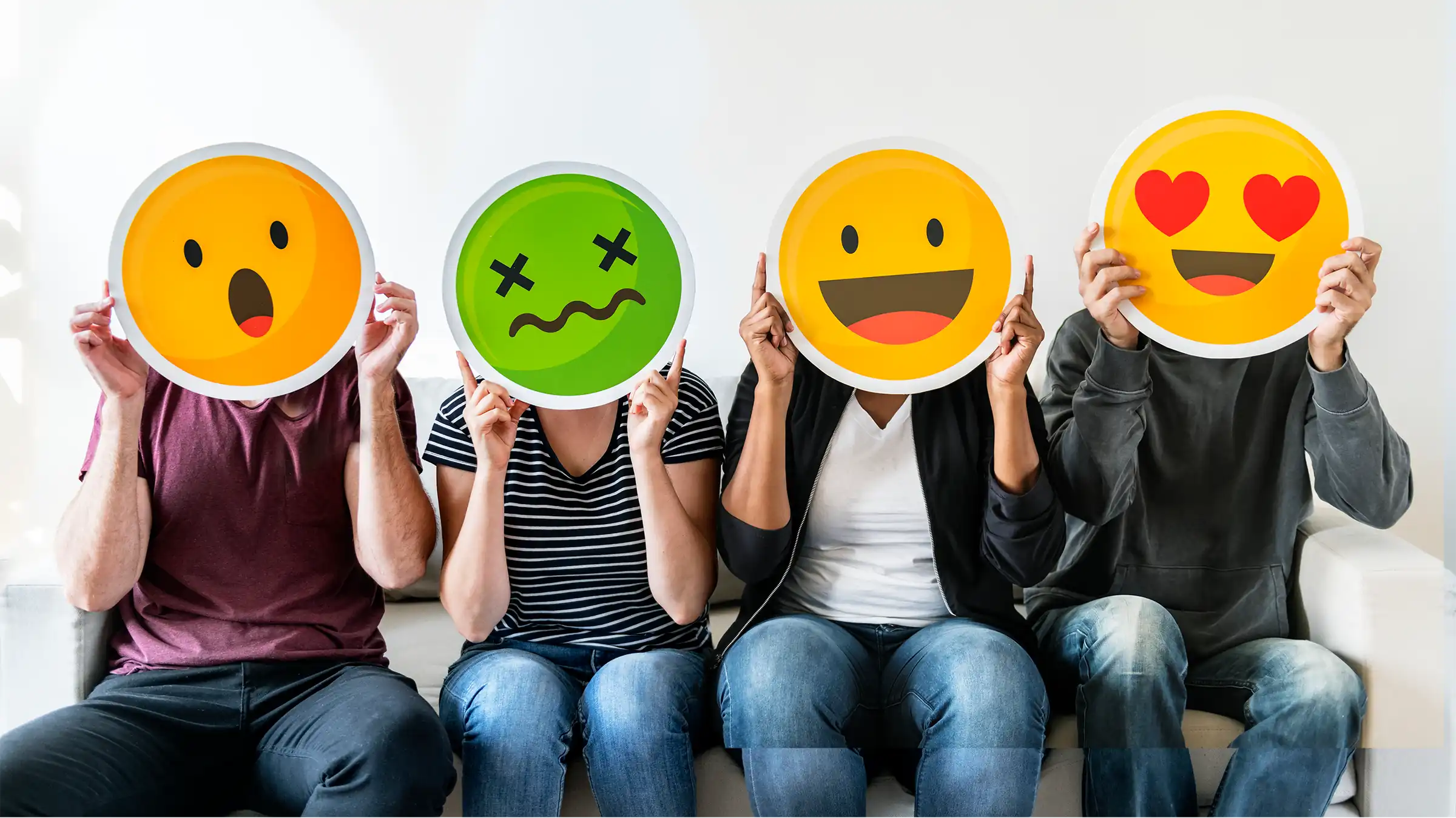 portrait of 4 people with emoji icons sitting next to each other on a couch