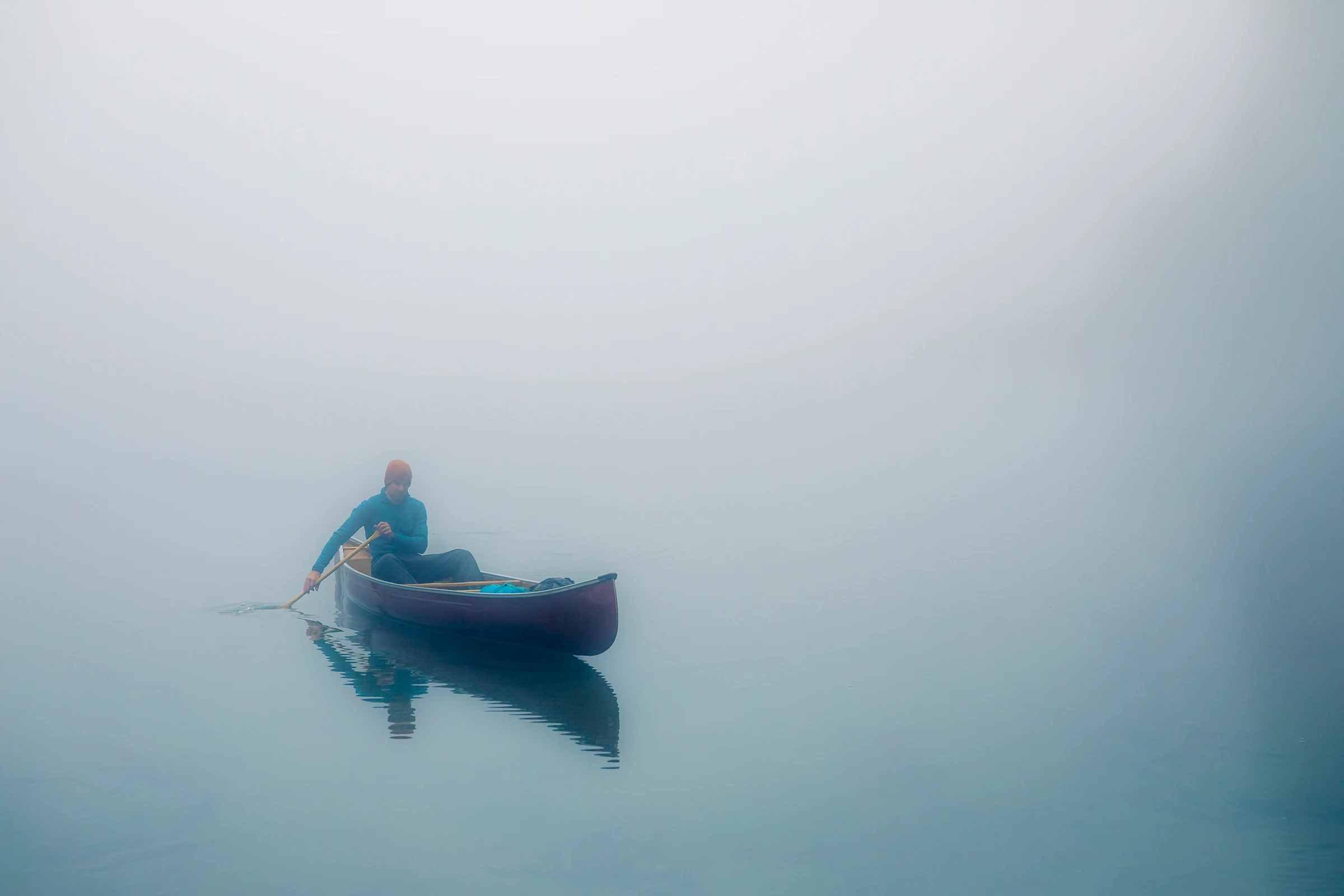 photo of a man in a canoe on a lake in very foggy conditions